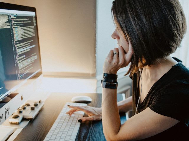 A woman working on software code on a computer.