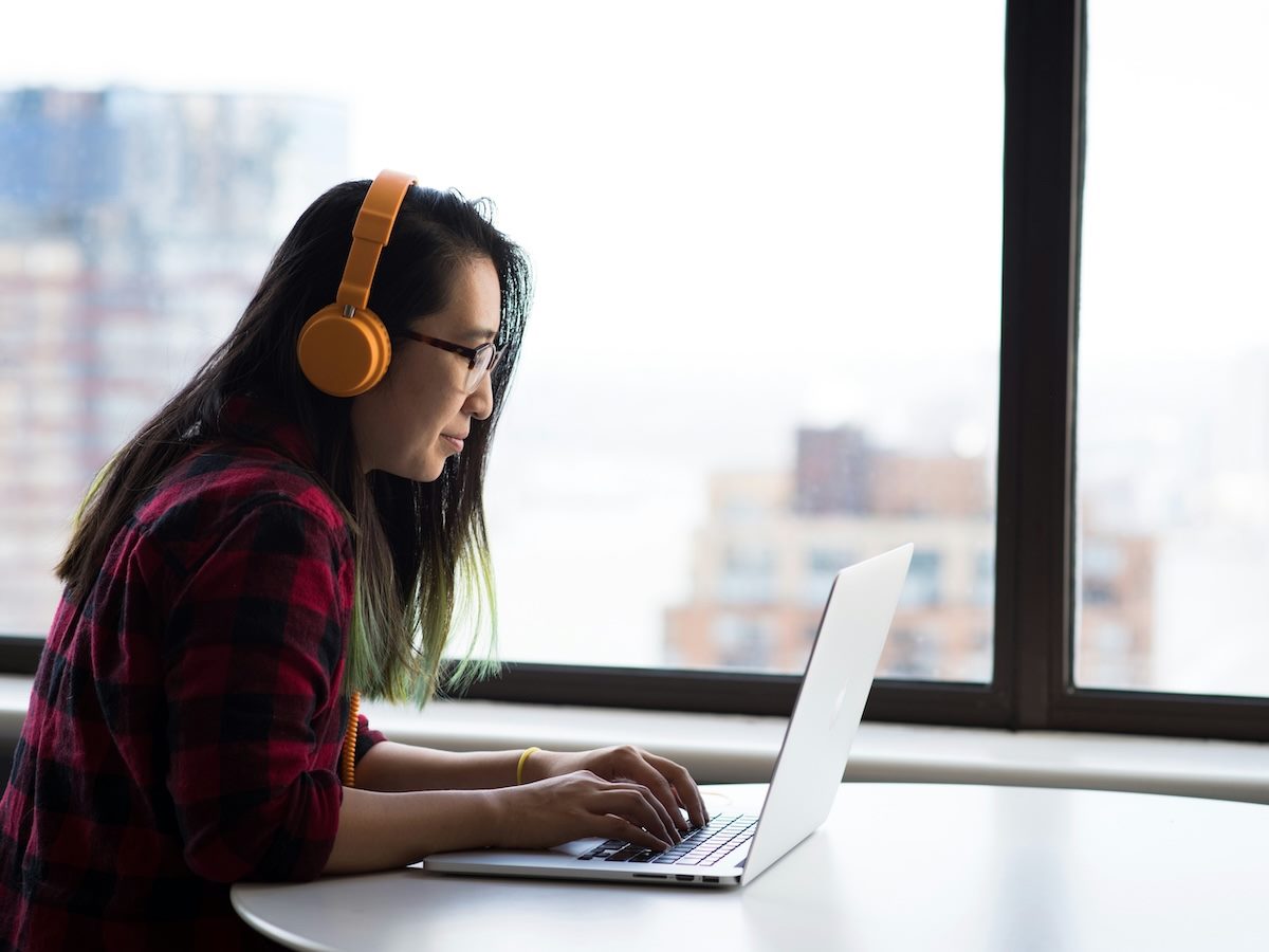 a woman technologist working on a laptop with headphones on