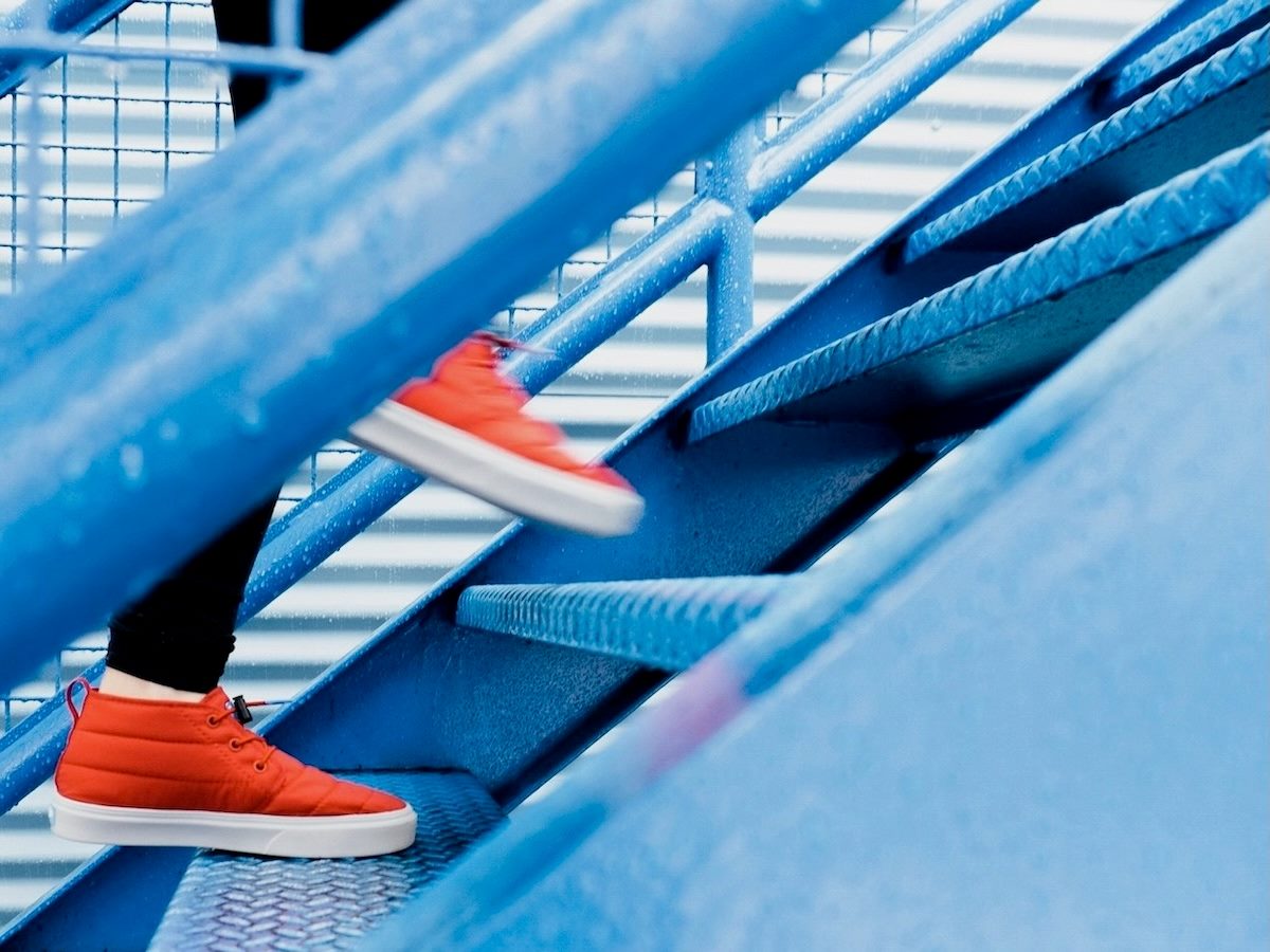 close up of a person's feet in orange shoes walking up some bright blue steps