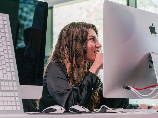An employee looks at a computer monitor on their work desk.