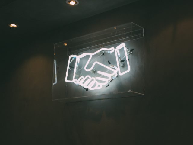 picture of a white neon sign showing a handshake