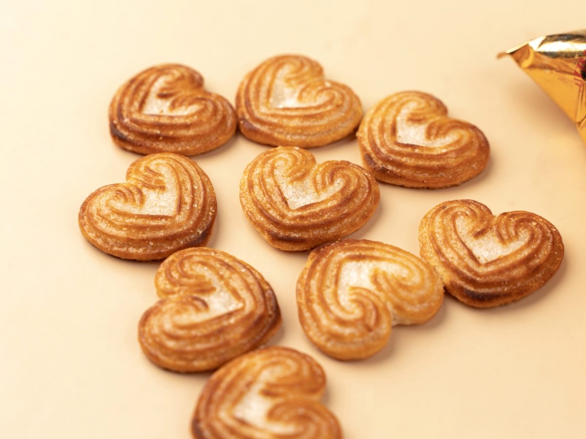 Heart-shaped Britannia biscuits arranged on a light background, with a partially visible golden wrapper on the side.