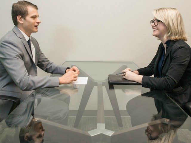 Man and a woman in business attire sitting at a conference table.