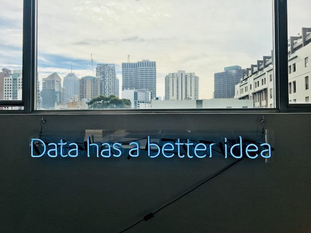 a neon sign that says "Data has a better idea" with window view of city overhead