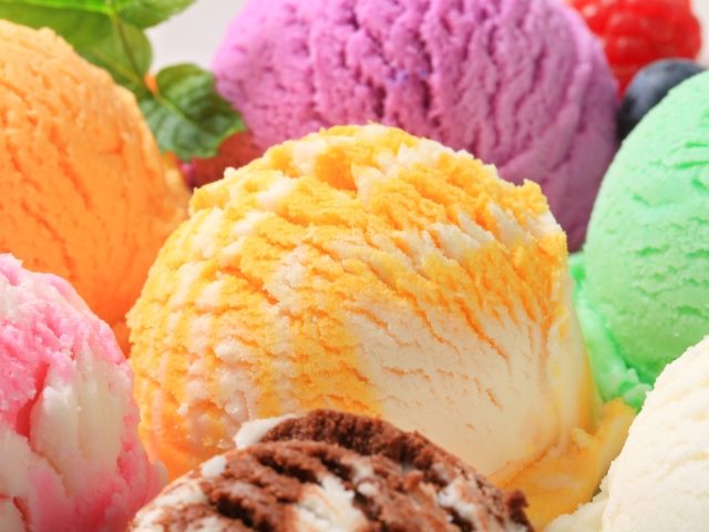 An array of colorful scoops of  ice cream flavors, including orange, green, red, and swirled pink and white and chocolate and white, symbolizing various use cases for generative AI in business.