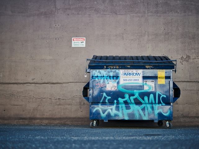 dumpster covered in graffiti against a wall