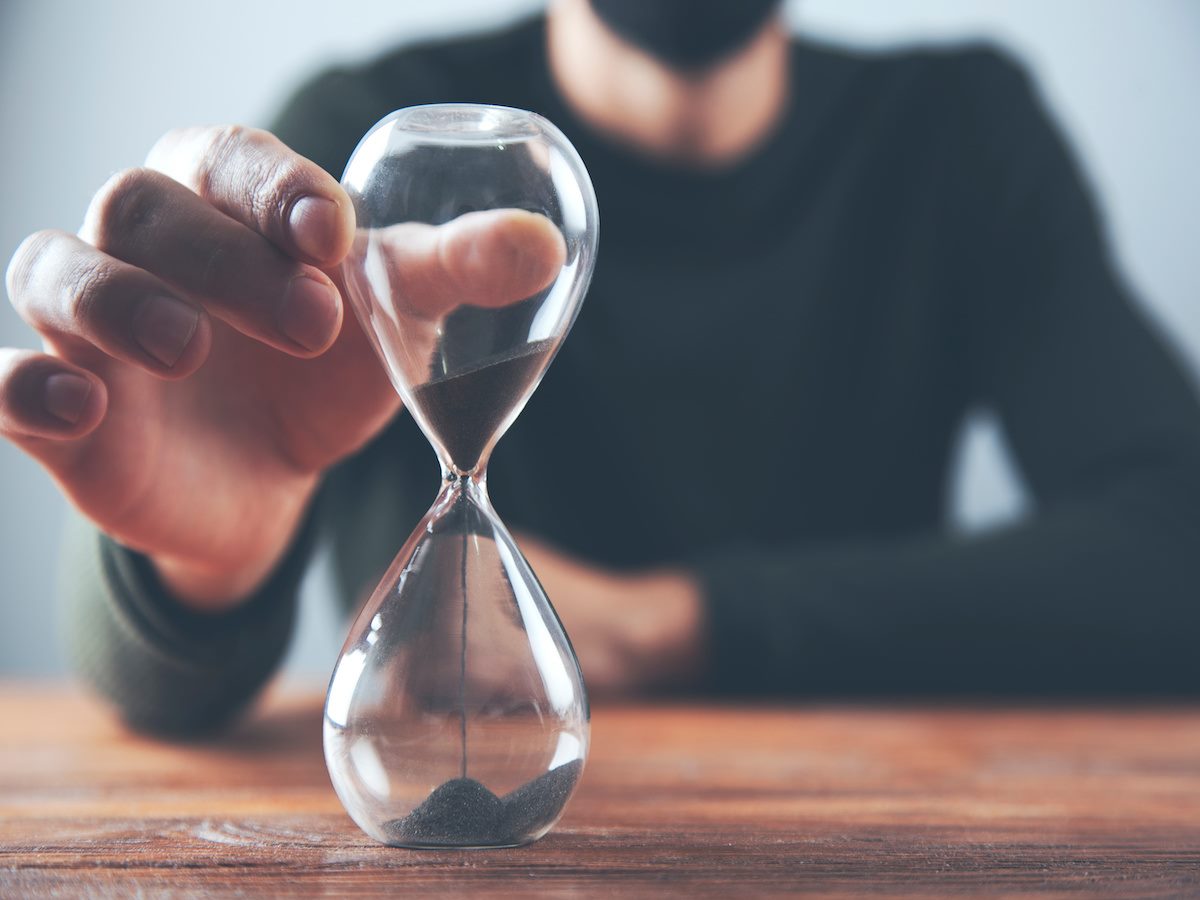 A person's hand reaching out toward an hour glass