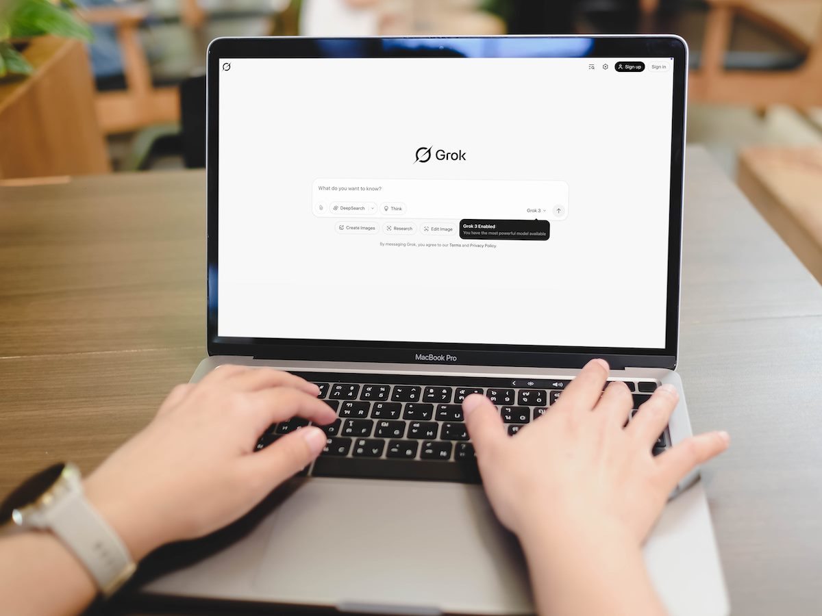 Person typing a prompt into the Grok AI chatbot on a laptop