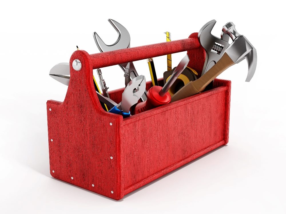A bright red wooden toolbox holds a variety of tools, such as a hammer, screwdriver and wrench among others against a white background in piece about AI content creation tools.
