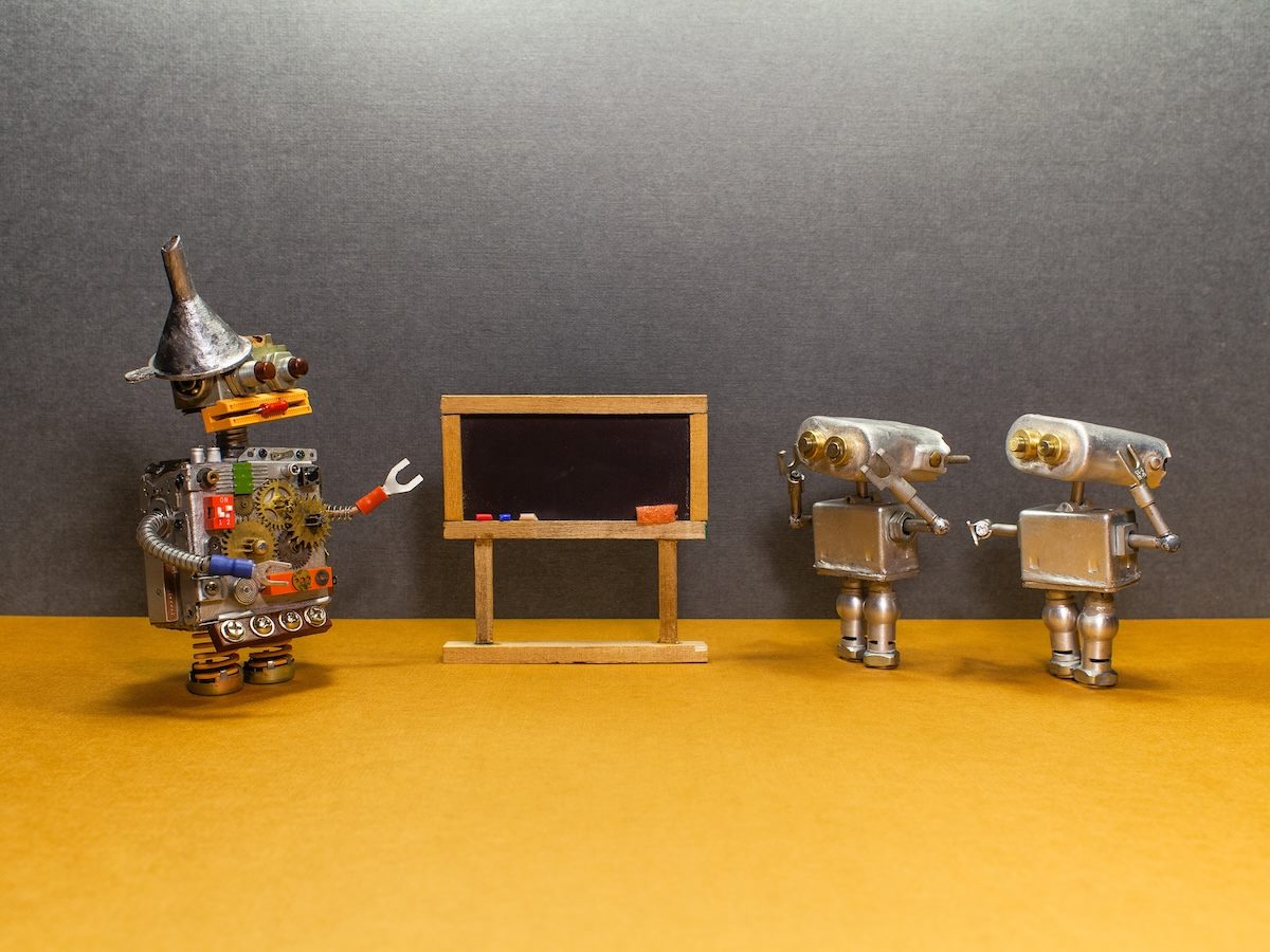 Classroom with empty black chalkboard, robot tutor teacher explaining theory, small robot students listening