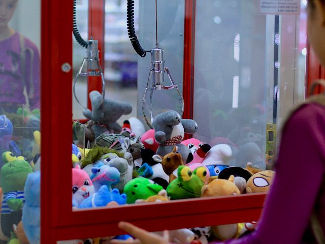 young girl playing the claw game at an arcade