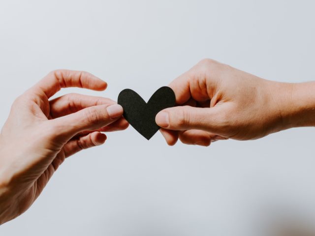 man and a woman holding a paper cutout of a heart