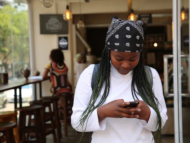 woman smiling while texting on her phone