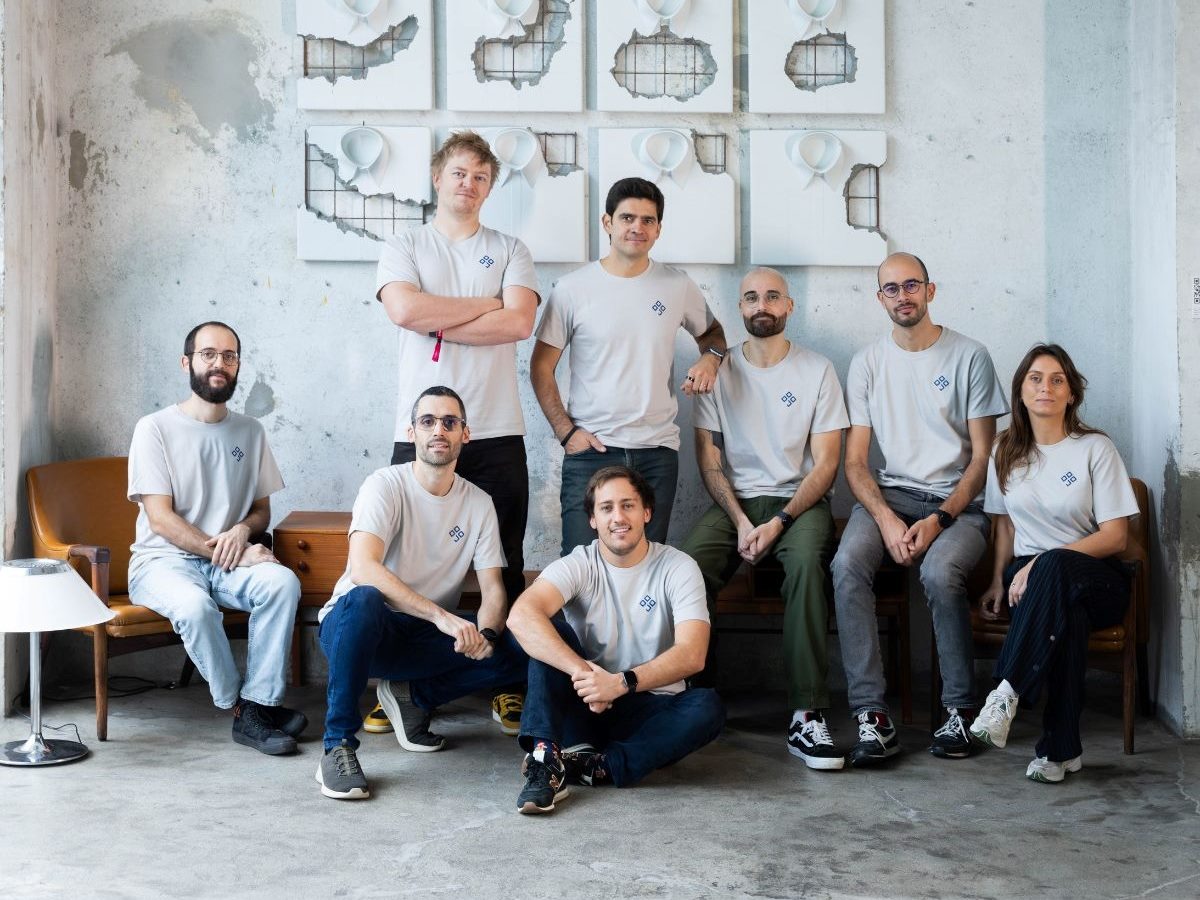  The DOJO AI team poses together in a studio space wearing branded company T-Shirts.