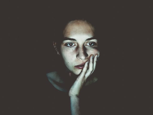 unhappy woman sitting in glow of computer