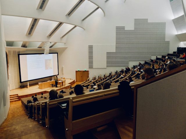 University students sit in a large lecture classroom.