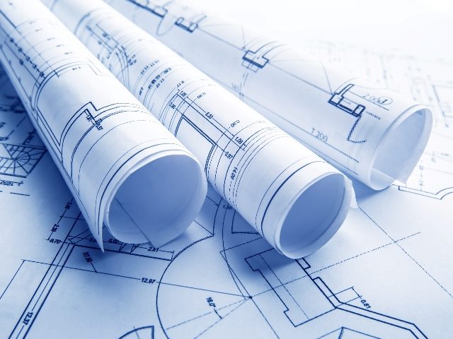 Three rolled scrolls of blueprints sit on top of a flat blueprint on a table or surface, suggesting the importance of a blueprint for AI in customer experience.