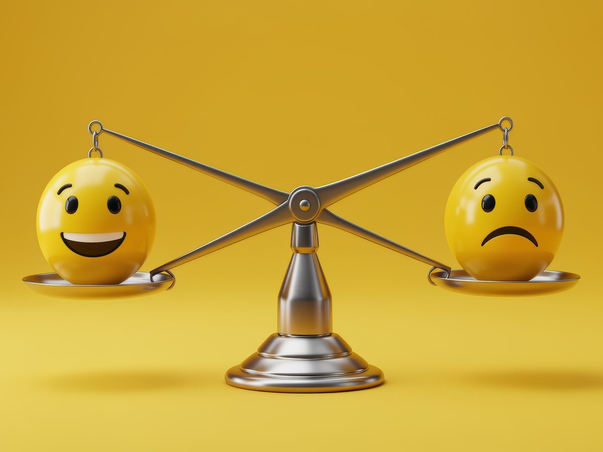 Two balls, one with a frowning face and one with a smiling face, on either side of a scale 