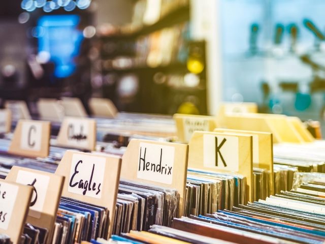 Close-up of vinyl records in a retail store with hand-written labels, including: The Doors and The Eagles as well as letters of the alphabet for searching.