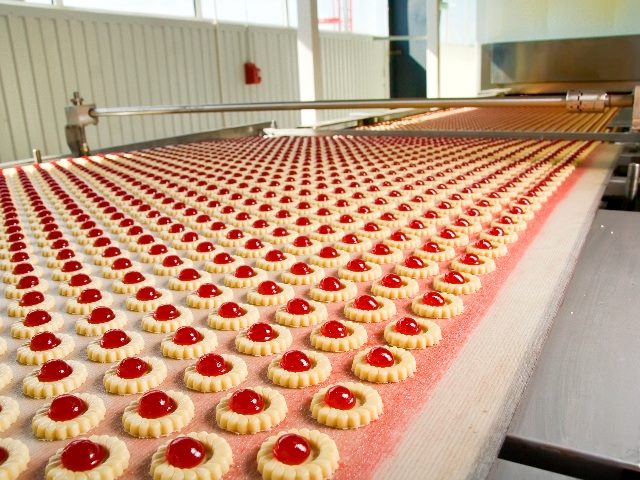 Factory production of red jelly filled cookies perfectly lined up row after row in story about AI Automation.