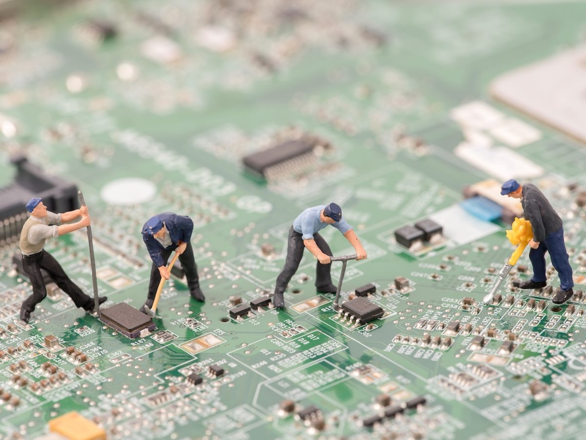 miniature figures working together on a computer chip, teamwork, collaboration concepts