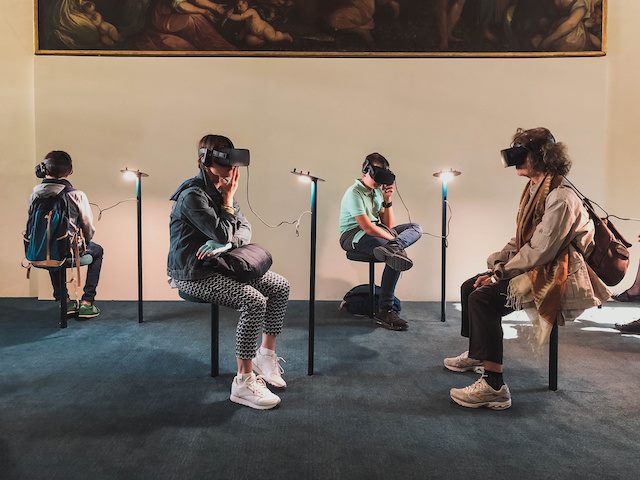 people sitting in an art gallery wearing VR goggles