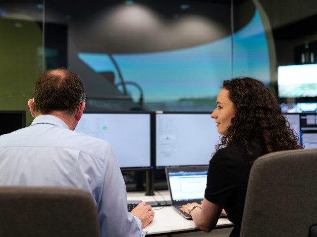 Employees work on an aerospace flight simulator.