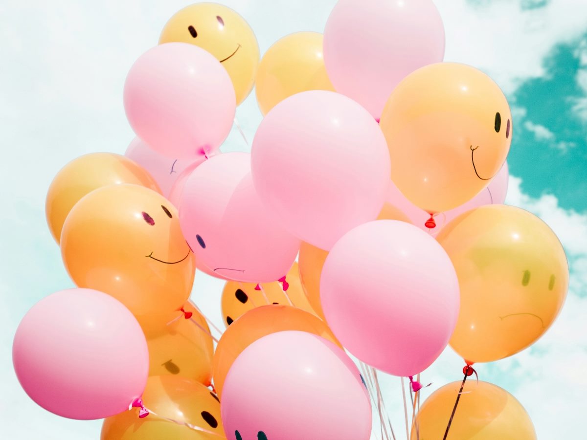 Balloon bunch colored pink and yellow with smiley faces on them.