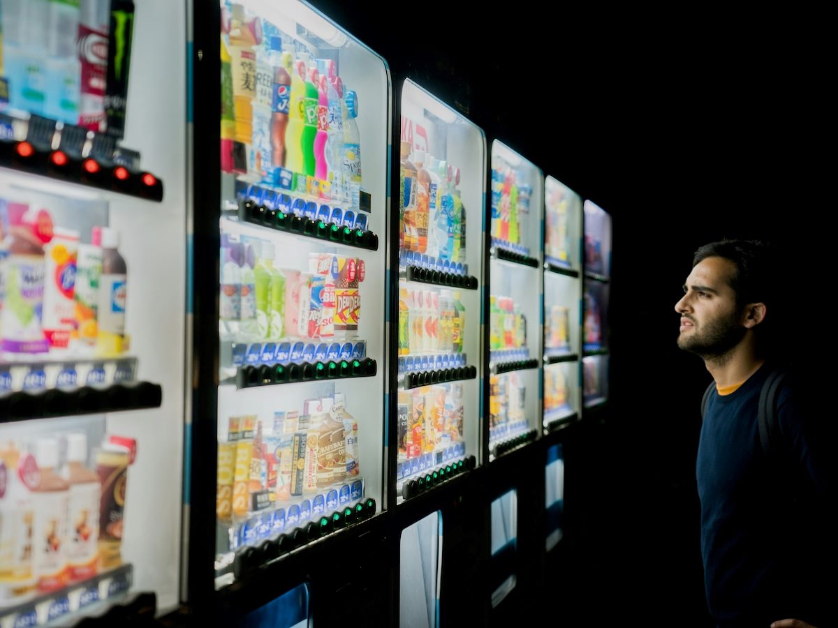 man looking at a large vending machine trying to make a selection