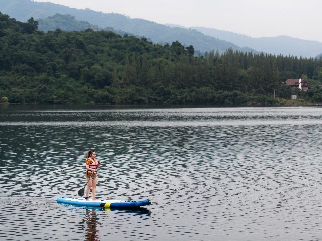 A woman on a stand up paddle board (SUP) on a calm lake. 