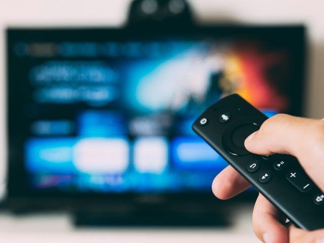 A consumer points a remote control at a TV.