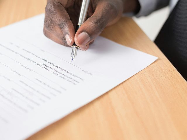 An employee signs a document on a desk.