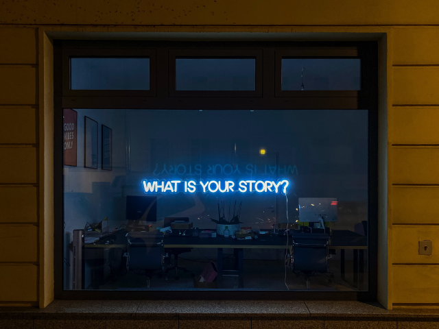 A storefront with a neon sign that reads, what is your story? - Voice of the customer concept