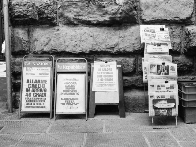 Several newspapers displayed on a city street sidewalk - newsbyte concept