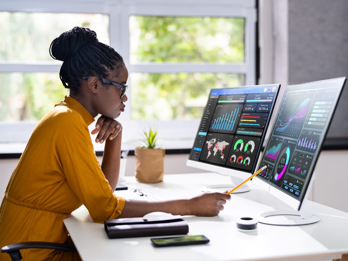 Woman looking at two screens that have data.