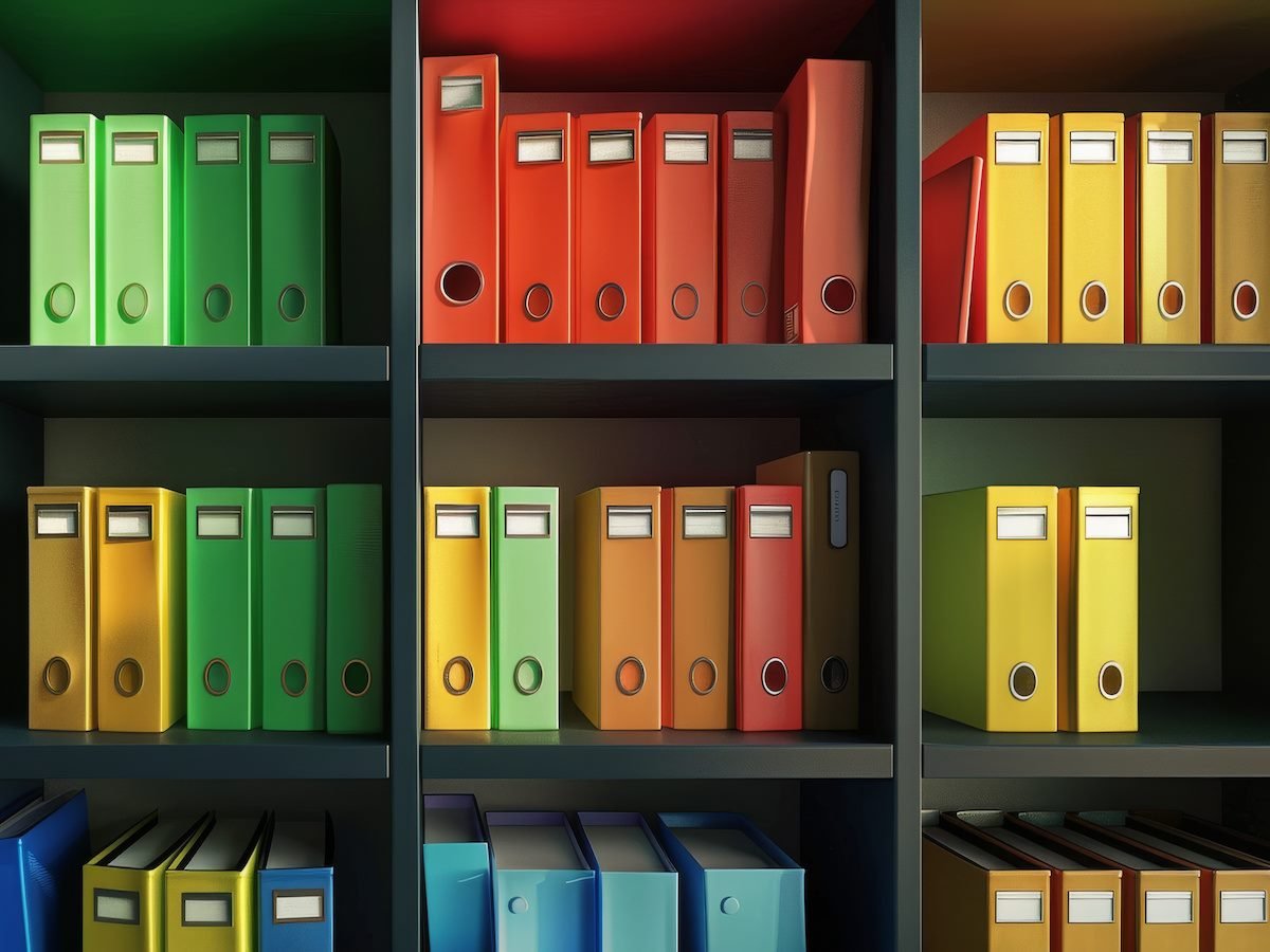 Colorfully organized binders line dark shelves
