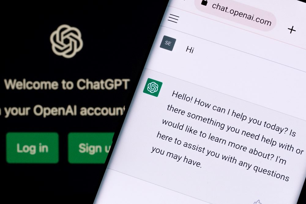 ChatGPT chatbot screen seen on a smartphone and laptop display with ChatGPT login screen on the background in piece about the one-year anniversary of the ChatGPT launch.