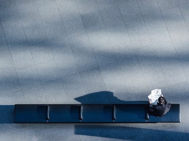 bird's eye view of man reading a paper on a bench