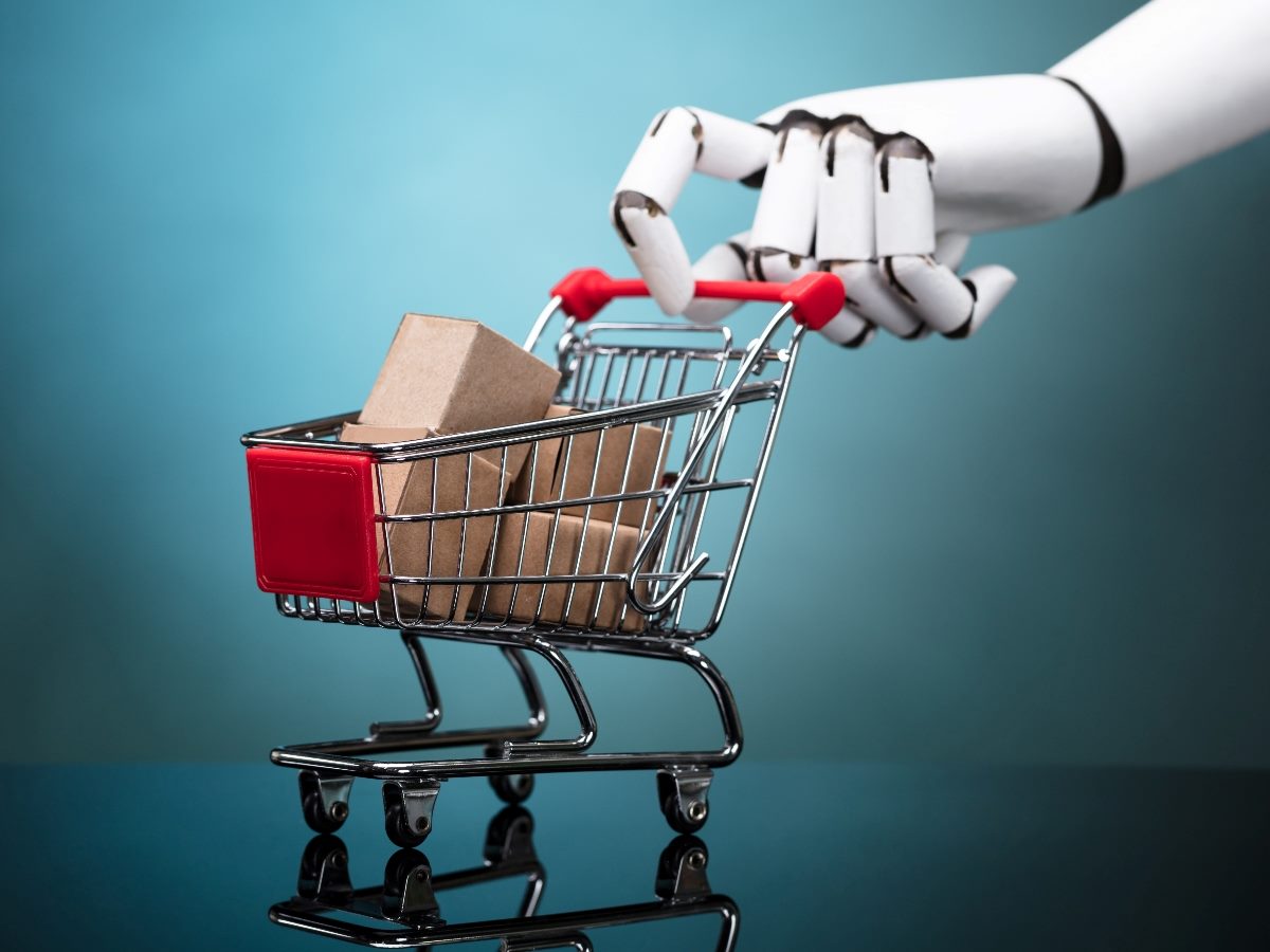 Robot hand holding shopping cart with cardboard boxes. 