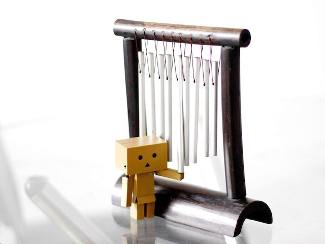 sad cardboard robot playing with windchimes