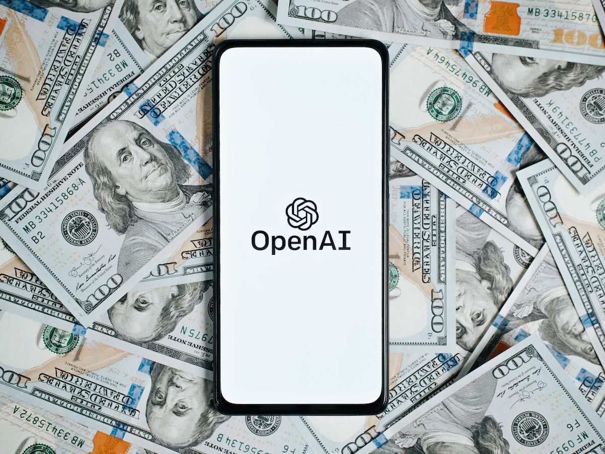 OpenAi company logo on screen of smartphone lying on money background