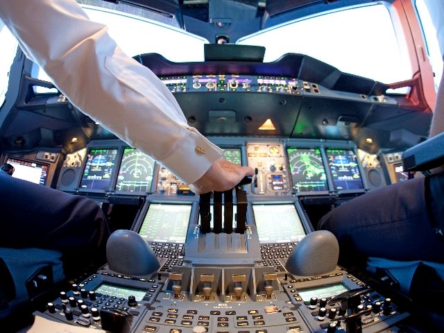 A pilot wearing a white uniform shirt grasps a lever in the cockpit during a flight with many dials and meters visible on the dashboard of the plane, signifying the need to oversee the use. of generative AI for customer experience and marketing.