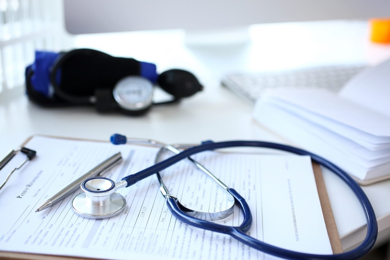 Stethoscope and silver pen lying on medical application form