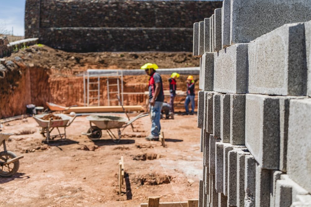Unknown persons outdoors working on a construction site on a sunny day, symbolizing the need to get your hands dirty with an AI strategy.