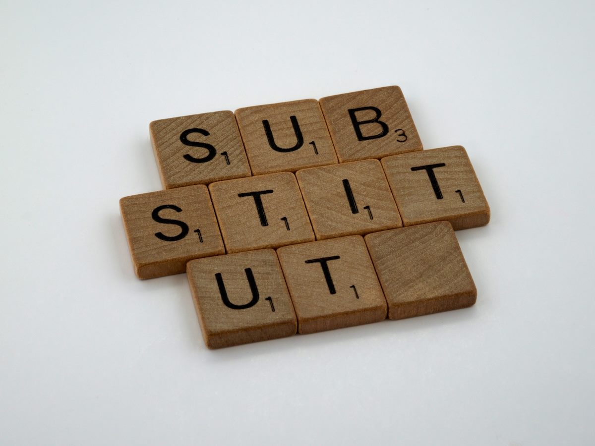 scrabble tiles arranged to spell out substitute, with the last letter missing