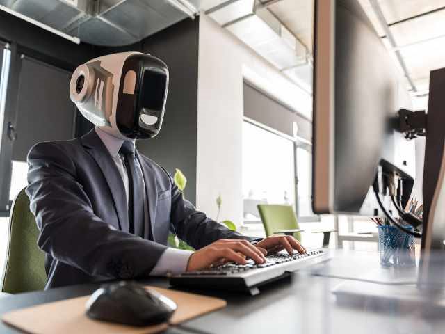 A robot in a suit working at a computer