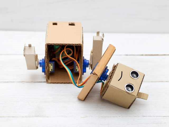  broken robot with hands on the white wooden background