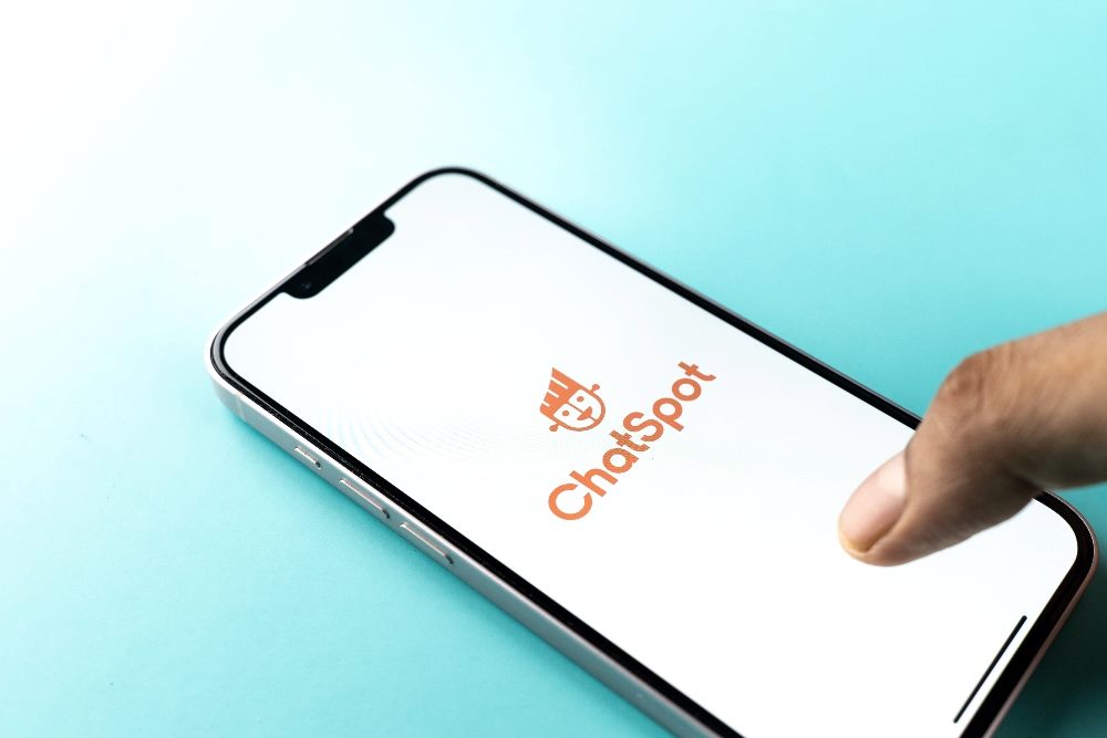 A smart phone reveals the name and logo of HubSpot's ChatSpot, a generative AI tool, in anticipation of a new suite of AI tools at the Inbound 2023 conference.