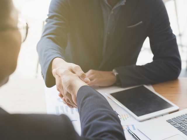 Woman and man shaking hand over table