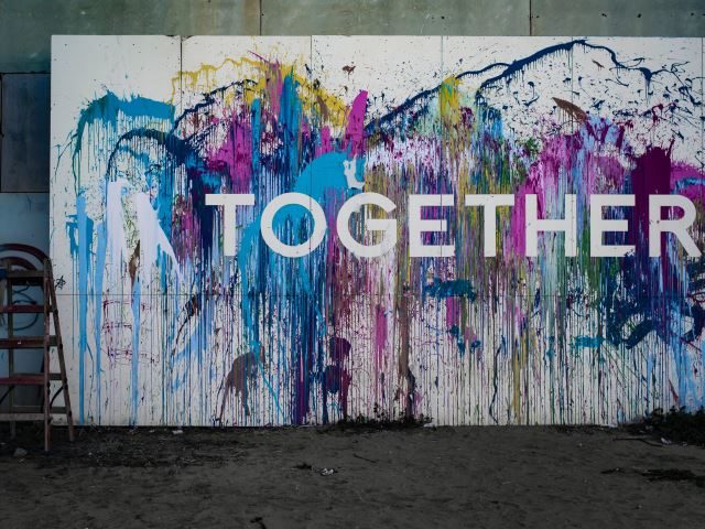 A wall with multi-colored graffiti that says Together. - Edge Computing and 5G Development Synergy Concept